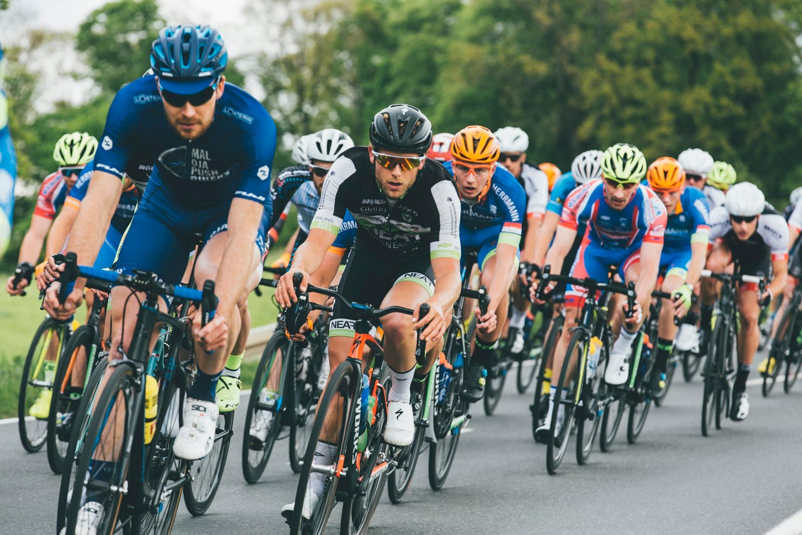 Tett peloton av landeveissyklister i full fart på asfaltvei — illustrasjonsfoto