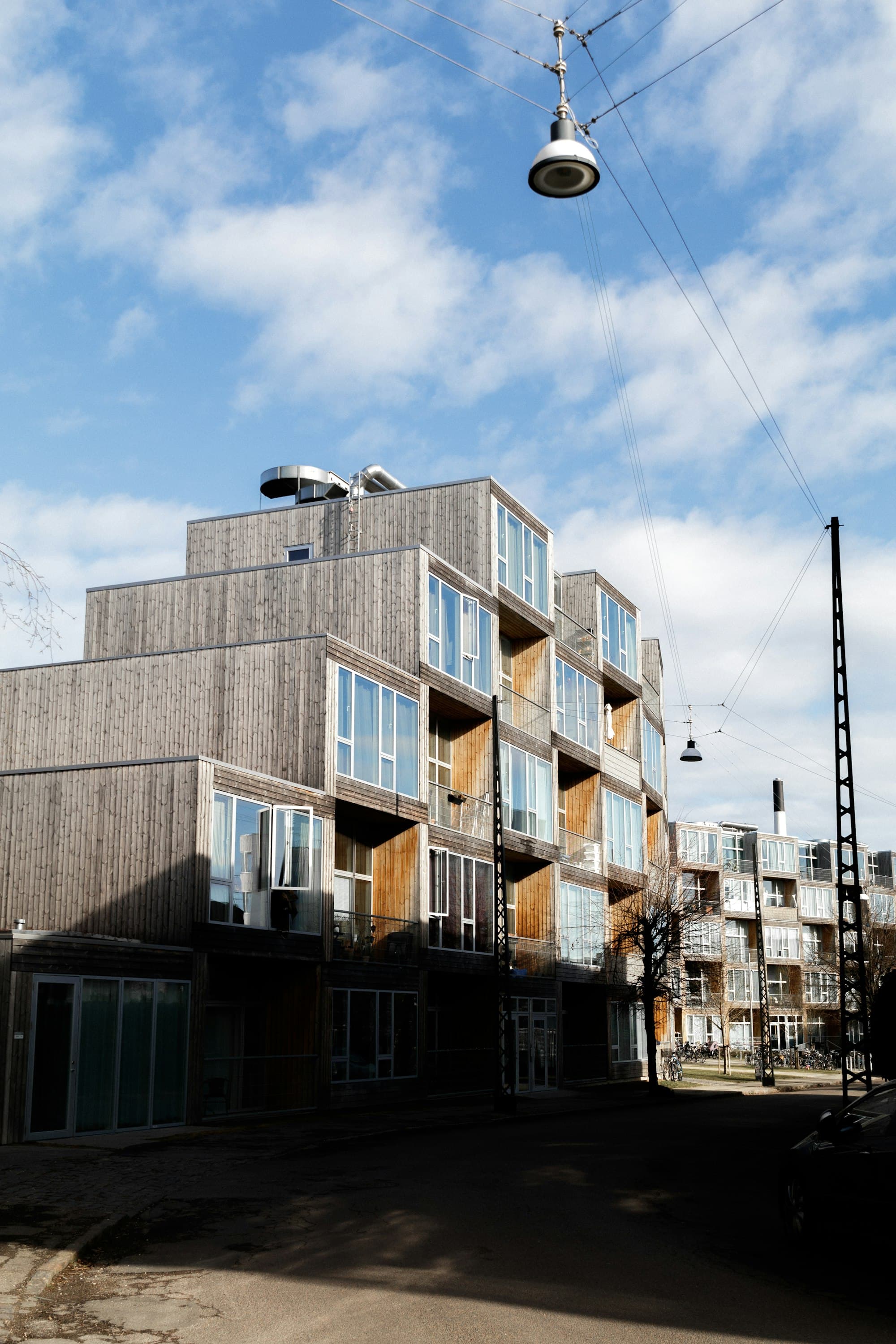 Nybygd lavblokk med trekledning og inntrukne balkonger langs en gate.