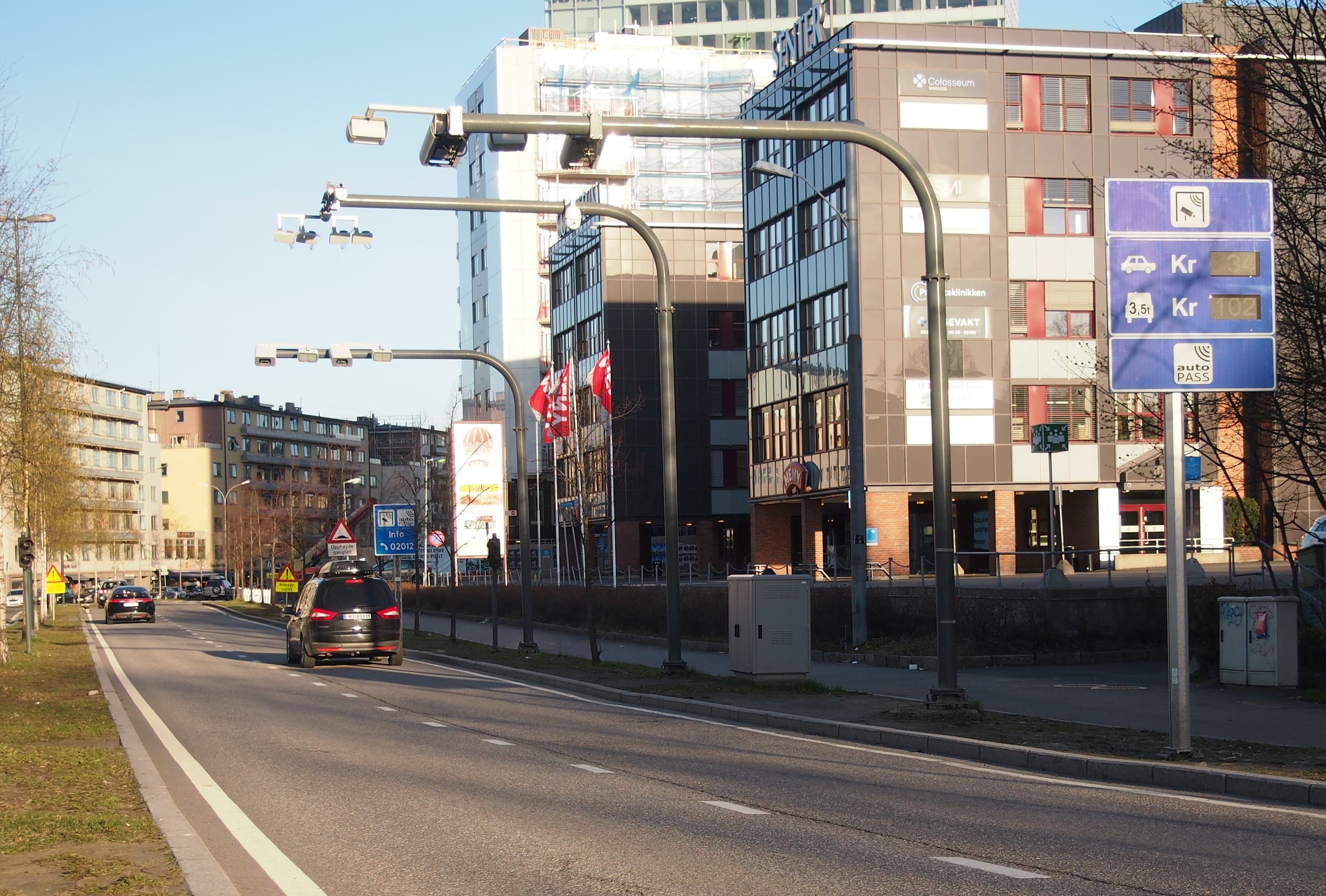 AutoPASS-bomstasjon over en bygate med biler og blått prisskilt – illustrasjonsfoto.