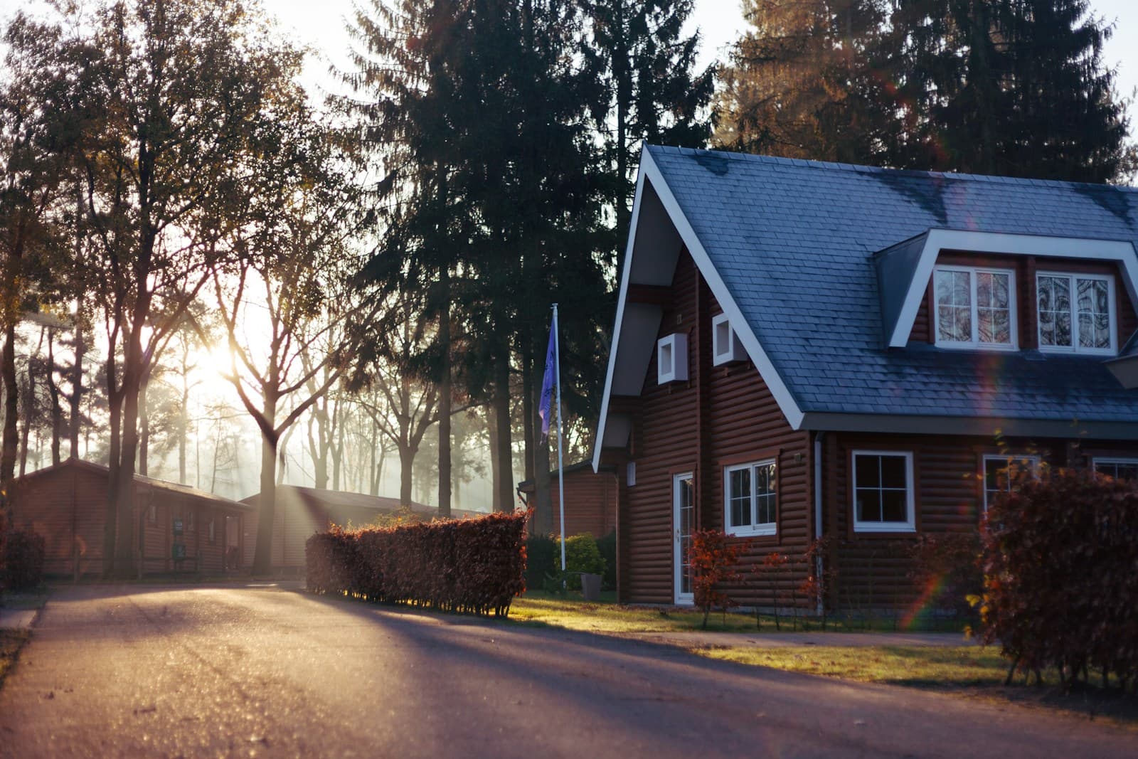 Rød-brunt trehus langs en boligveg i morgenlys – illustrasjonsfoto for boligbygging og reguleringsplan.