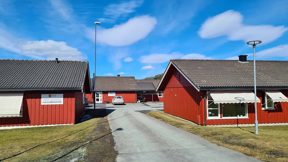 Flå eldresenter på Ler – røde trebygg med skiltet «FLÅ ELDRESENTER» langs en asfaltert innkjørsel.